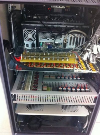 Interior of a server rack showing a power supply, expansion cards, and a yellow terminal strip with many red-connected wires and cables on the right.