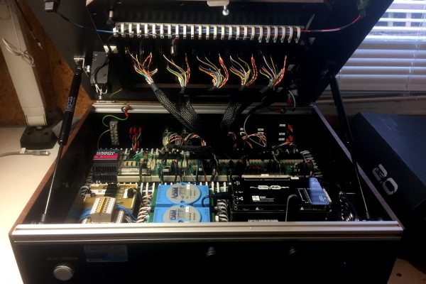 Open electronics cabinet exposing dense wiring, circuit boards, and blue modules in a control system edge.