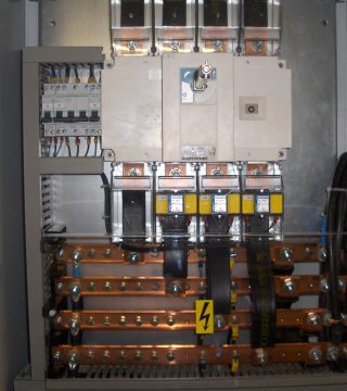 Industrial electrical switchgear inside a metal cabinet with copper busbars and circuit breakers.